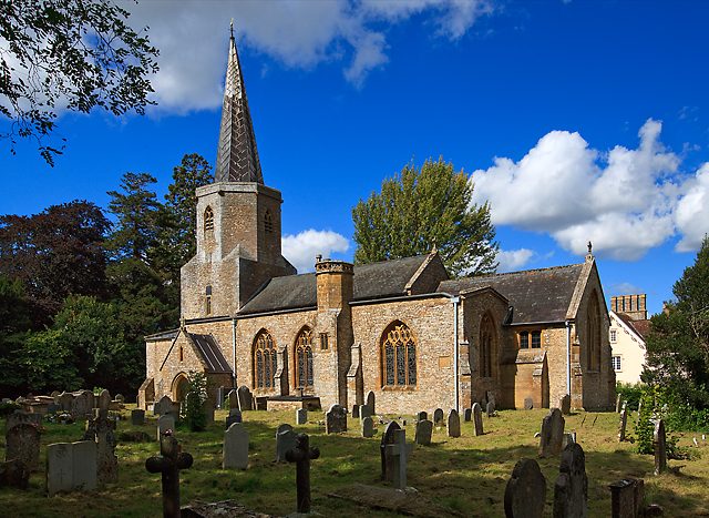The church of St Andrew and St Mary, Pitminster, from the south-east: a square tower rising to an octagon with a lead spire, the churchyard in front